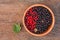 Sweet, black and red currant and green leaves in wooden bowl.