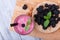 Sweet blackberries in a new plate on a gray wooden background. Raw and ripe berries with mint and smoothie on a desk.