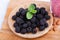 Sweet blackberries in a wooden plate on a white background. Raw and ripe berries with mint and smoothie on a desk.