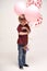 Sweet boy holding balloons with red and pink hearts. Valentines day or kids healthcare, medical concept