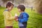 Sweet boys in the park, holding bottle with smoothie, drinking