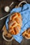 Sweet braided buns with sesame seeds on a blue kitchen towel.