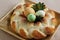 Sweet braided homemade bread with three easter eggs and twig with leaves decorated on wooden plate