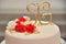 Sweet cakes in the form of red roses decorate the wedding cake with more decorative twigs of white cream
