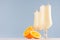 Sweet cheerful oranges milkshakes in two glass decorated slices fruit, striped straws on light pastel blue background.