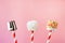 Sweet chewy marshmallow and lollipops on straw decorated with melted chocolate and cake sprinkles on pink background. Kids will lo