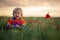 Sweet child, blond boy, playing in poppy field on a partly cloudy day, dramatic sky