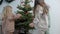 Sweet children in stylish casual suits decorate a Christmas tree