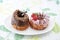 Sweet chocolate almond and strawberry cake doughnuts on a plate on tablecloth