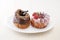 Sweet chocolate almond and strawberry cake doughnuts on a plate on tablecloth