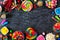 Sweet and colorful candy buffet frame, top view table scene over a dark stone background