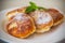 Sweet cooked cheesecakes in powdered sugar in a plate