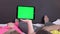 Sweet couple on bed watching something on white tablet gadget, green screen