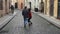 Sweet couple have romantic time while honeymoon trip in old european town. Young lovers holding hands running on street
