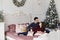 Sweet couple hugging each other on the bed in bedroom decorated for Christmas. Handsome man and brunette young woman in