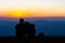 Sweet couple silhouette sitting on the mountain with sunset