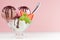 Sweet creamy ice cream - pink, white, brown in bowl with spoon, mint, strawberry, chocolate sauce on white wood table and pink.