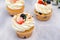 Sweet cupcakes for party. Fresh cupcakes decorated with cream cheese, blueberry and strawberry on modern concrete background