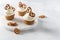 Sweet cupcakes with whipped cream and brezel on white marble tray. Bakery, confectionery banner, cookbook recipe, menu. Side view