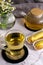 Sweet delicious eclairs and tea in a glass cup on the table with a vase of chamomile flowers