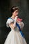 Sweet delight. Elegant woman, royal person, queen or princess in white medieval outfit tasting jelly candy on dark