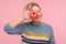 Sweet dessert, confection. Portrait of cheerful woman with short curly hair in sweater holding doughnut