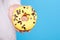 Sweet donut with chocolate drops in hand, isolated on blue background