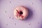 Sweet doughnut with purple icing on pastel background. Tasty donut on violet texture, copy space, top view