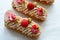 Sweet eclairs decorated with raspberries