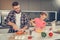 Sweet fair-haired girl in a pink t-shirt and her father cooking omelet together