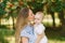 Sweet and gentle young woman a European mother holds her little son in her arms and kisses him near the branches with red Rowan