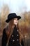 Sweet girl in a cap with the deer in autumn in a field of dry grass