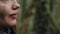 Sweet girl is drinking from a thermos in a close-up. There is moss-covered fairytale forest on the background