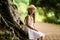 Sweet girl in a hat and white dress walks in the botanical garden on a summer day