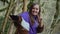 A sweet girl makes a peace-selfie on the background of the moss-covered trees in a foggy boxwood forest.