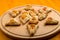 Sweet gomentashi cookies for the Purim holiday on a chalkboard are laid out on a blackboard on a light table.