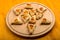 Sweet gomentashi cookies for the Purim holiday on a chalkboard are laid out on a blackboard on a light table.