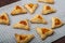 Sweet gomentashi cookies for the Purim holiday on a chalkboard laid out on a gray napkin.