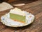Sweet green tea cheesecake topping with white chocolate put on a white plate