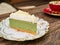 Sweet green tea cheesecake topping with white chocolate put on a white plate