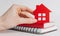 Sweet home. Estimating and paying house tax. Woman holding red house with her hands and notepad in copy space white background