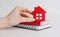 Sweet home. Estimating and paying house tax. Woman holding red house with her hands and notepad in copy space white background