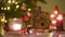 Sweet homemade gingerbread house decorated candies and glazed is standing on table near Christmas tree with decorations lights