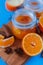 Sweet jam from oranges in small jars with fresh cutted oranges, cinnamon and anice on the blue table