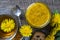 Sweet jam from ripe yellow petals of dandelion flowers, orange, lemon and sugar on the wooden table with tea and cookies, top view