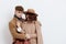 a sweet, joyful, pleasant stylish couple stands on a white background in autumn coats and gently hug each other