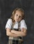 Sweet junior schoolgirl with blonde hair crying sad in front of school classroom blackboard