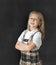 Sweet junior schoolgirl with blonde hair standing and smiling happy in blackboard background