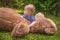 Sweet little baby boy having fun outdoors playing with his giant teddy bear in the park