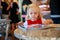 Sweet little blond girl looks magazine in a cafe